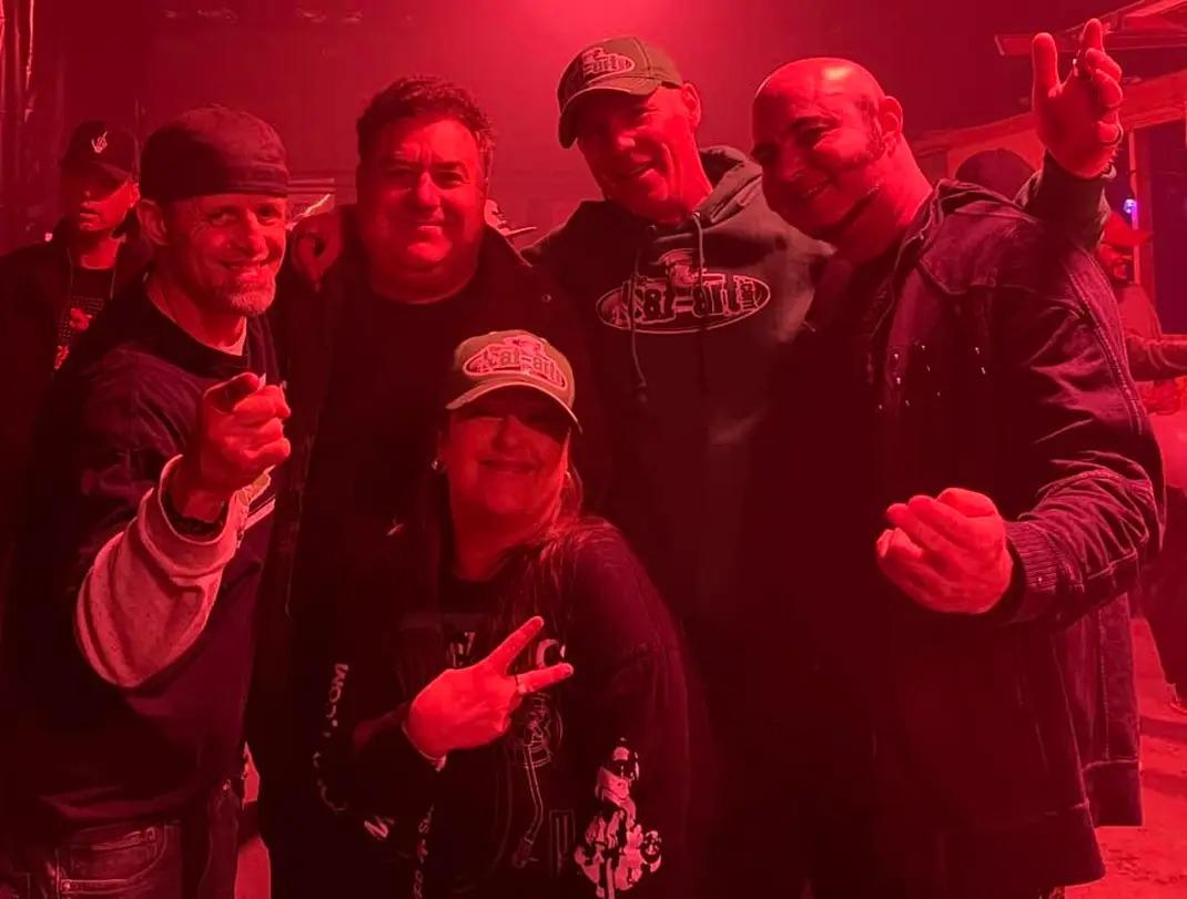 DJ Natural Nate® with four TLA crew members throwing up signs under red fog lighting